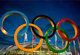 The Olympic rings stand in front of a venue where athletes compete for medals.